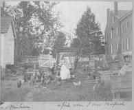 SA0418 - Portrait of Jane Sutton with chickens in a yard between buildings. Identified on the back., Winterthur Shaker Photograph and Post Card Collection 1851 to 1921c
